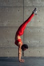 Young fit woman doing handstand exercise in studio.