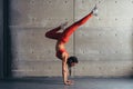 Young fit woman doing handstand exercise in studio.