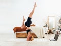 Young fit woman doing headstand exercise at home