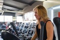 Young fit woman at the gym using elliptical cross trainer. Female athlete at a fitness room working out on an exercise bike Royalty Free Stock Photo