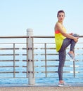 Young fit woman looking aside and stretching at embankment Royalty Free Stock Photo