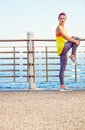 Young fit woman looking aside and stretching at embankment Royalty Free Stock Photo