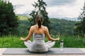 Young fit woman practising meditation on yoga mat at sunny mountains. Healthy lifestyle outdoor