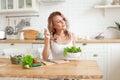 Young fit woman preparing and eating vegetable salad in her kitchen. Healthy lifestyle and healthy eating concept Royalty Free Stock Photo