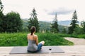 Young fit woman relaxing or practising meditation on yoga mat at sunny mountains. Outdoor workout Royalty Free Stock Photo