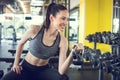 Young fit woman sitting on exercise bench and lifting kettle bell in gym. Royalty Free Stock Photo