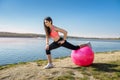 Young fit woman in sportswear during fitness time and exercising with ball at the lake. Healthy lifestyle Royalty Free Stock Photo