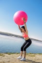 Young fit woman in sportswear during fitness time and exercising with ball at the lake. Healthy lifestyle Royalty Free Stock Photo