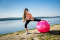 Young fit woman in sportswear during fitness time and exercising with ball at the lake. Healthy lifestyle Royalty Free Stock Photo