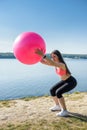 Young fit woman in sportswear during fitness time and exercising with ball at the lake. Healthy lifestyle Royalty Free Stock Photo