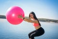 Young fit woman in sportswear during fitness time and exercising with ball at the lake. Healthy lifestyle Royalty Free Stock Photo