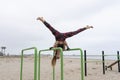 Young fitness female doing hand stand push ups exercise in parallel bars on beach.Athletic sportswoman during workout in Royalty Free Stock Photo