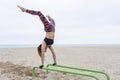 Young fitness female doing hand stand push ups exercise in parallel bars on beach.Athletic sportswoman during workout in Royalty Free Stock Photo