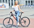 Young fitness girl with sport bike is walking in the city