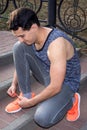 Young fitness man ties up shoelaces on his sport footwear