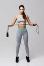 Young fitness sportive girl posing looking at camera holding jumping rope over white background. Royalty Free Stock Photo