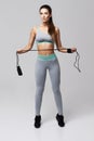 Young fitness sportive girl posing looking at camera holding jumping rope over white background. Royalty Free Stock Photo