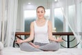Young fitness woman in casual wear practicing yoga on bed in bedroom at home in Morning . sport girl doing meditating in lotus