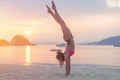 Young fitness woman doing handstand exercise on beach at sunrise. Sporty girl in bikini practicing yoga seashore. Royalty Free Stock Photo