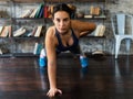 Young fitness woman doing push ups exercise on one hand on floor