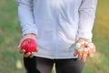 Young fitness woman holding in hands red apple and donut