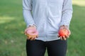 Young fitness woman holding in hands red apple and donut