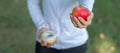 Young fitness woman holding in hands red apple and donut