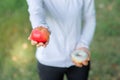 Young fitness woman holding in hands red apple and donut