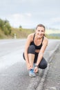 Young fitness woman lace up her trainers before jog