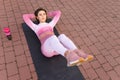 Young fitness woman in pink sportswear lying on yoga mat and doing abdominal crunch exercise. Royalty Free Stock Photo