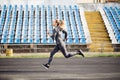 Young fitness woman running during sunny morning on stadium track Royalty Free Stock Photo