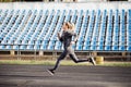 Young fitness woman running during sunny morning on stadium track Royalty Free Stock Photo