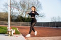 Young fitness woman in sportswear doing standing exercise for thorax muscles with resistance band during outdoors Royalty Free Stock Photo