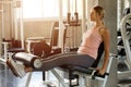 young fitness woman in sportswear exercises open legs muscles with push machine in gym . sport girl workout healthy lifestyle.