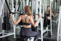 young fitness woman in sportswear exercising building muscles with machine Cable Crossover in sport gym . workout Royalty Free Stock Photo