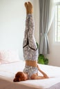 Young fitness woman in sportwear practicing yoga on bed in bedroom at home in Morning . sport girl doing supported Shoulder stand Royalty Free Stock Photo