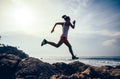 Woman trail runner running to rocky mountain top