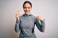Young fitness woman wearing sport workout clothes holding paper with diet word with surprise face pointing finger to himself