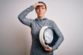 Young fitness woman wearing sport workout clothes holding scale for healthy weight stressed with hand on head, shocked with shame