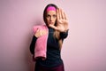 Young fitness woman wearing sport workout clothes using towel over pink background with open hand doing stop sign with serious and Royalty Free Stock Photo