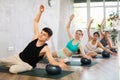 Young fitness woman and man in activewear working out with soft ball pilates on mat while doing upper body training in Royalty Free Stock Photo