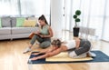 Young fitness and yoga instructor working in your home. Sporty educated woman helping young girl at her apartment at in home worko