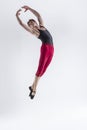 Contemporary Ballet of Young Flexible Athletic Man Posing in Red Tights in Flying Dance Pose With Hands Connected in Studio on