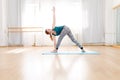 Young flexible blonde woman practicing triangle pose in yoga center Royalty Free Stock Photo