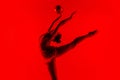 Young flexible female gymnast isolated on red studio background