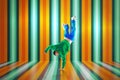 Young flexible sportive man dancing breakdance in green and blue sport uniform outfit against vivid striped studio