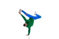 Young flexible sportive man dancing breakdance in green and blue sport uniform outfit against white studio background.