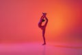 Young flexible teen girl rhythmic gymnast in motion, action isolated over pink background in neon light. Sport, beauty Royalty Free Stock Photo