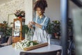 Young florist in apron creating beautiful simple daisy bouquet in craft paper Royalty Free Stock Photo