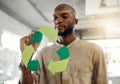 Young focused african american businessman drawing a recycle symbol on a glass window in an office at work. One serious Royalty Free Stock Photo